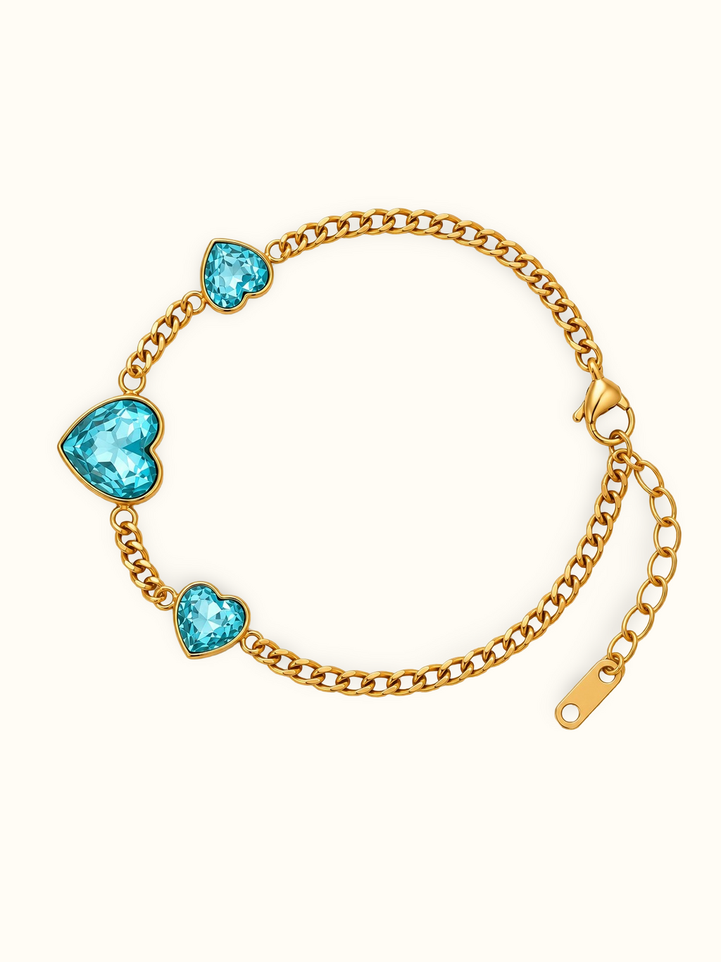 Gold chain bracelet with three heart-shaped turquoise blue crystals, displayed on a clean off-white background.