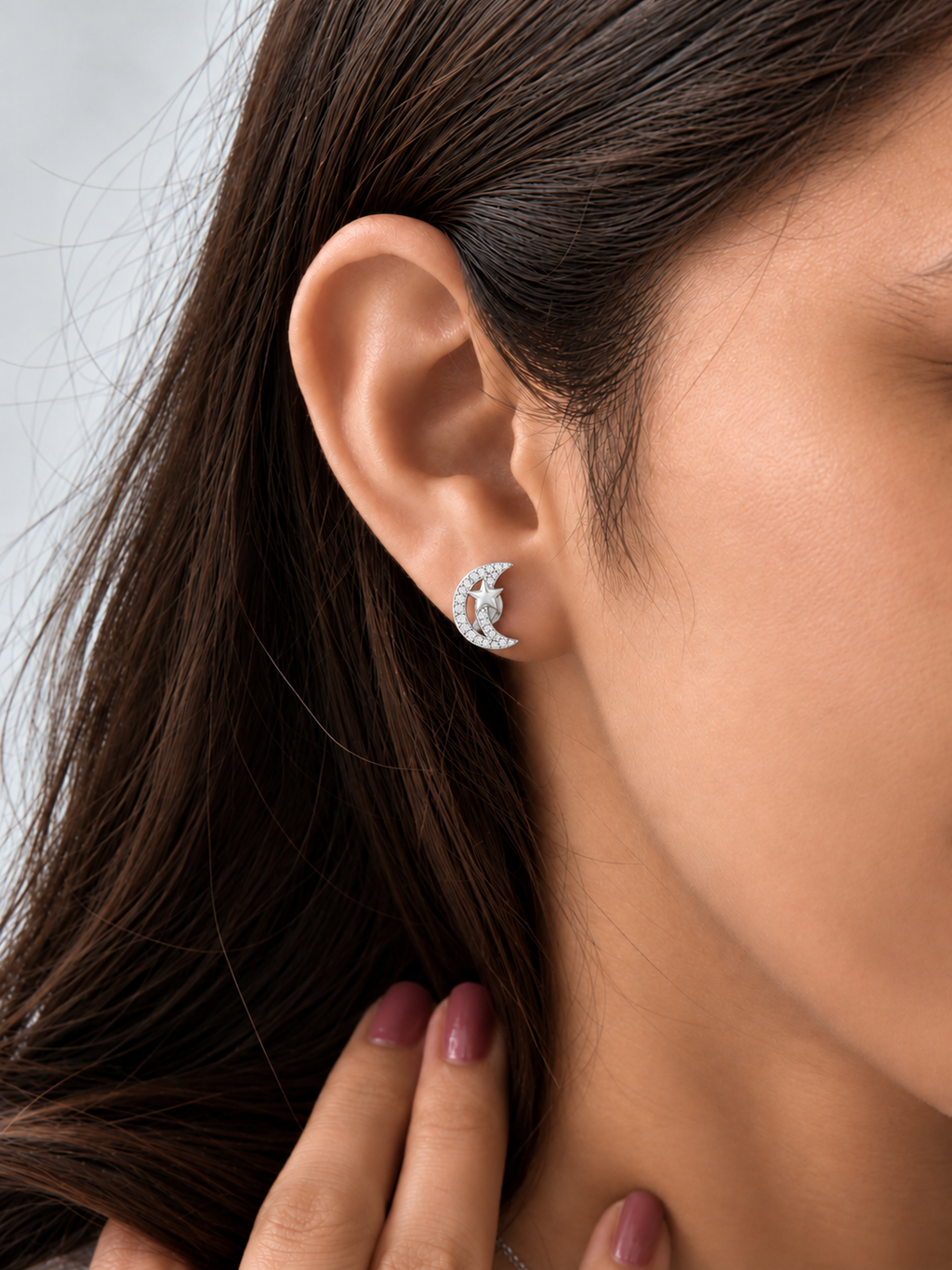 Model wearing silver crescent moon and star stud earrings embellished with sparkling clear zircons.