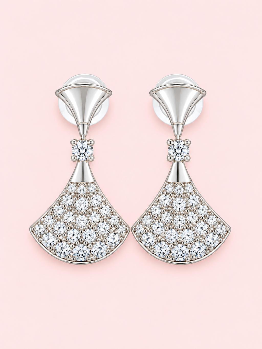 Silver fan-shaped drop earrings with sparkling clear stones displayed against a soft pink background.