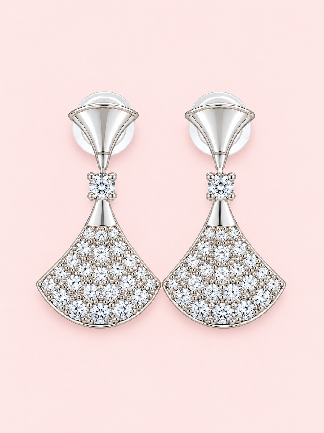 Silver fan-shaped drop earrings with sparkling clear stones displayed against a soft pink background.