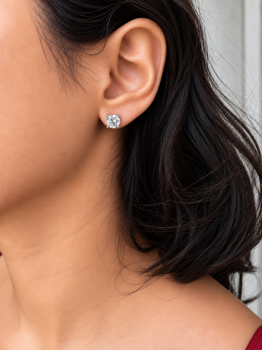 Silver-tone round solitaire stud earrings with large clear stones in four-prong settings worn by a model.