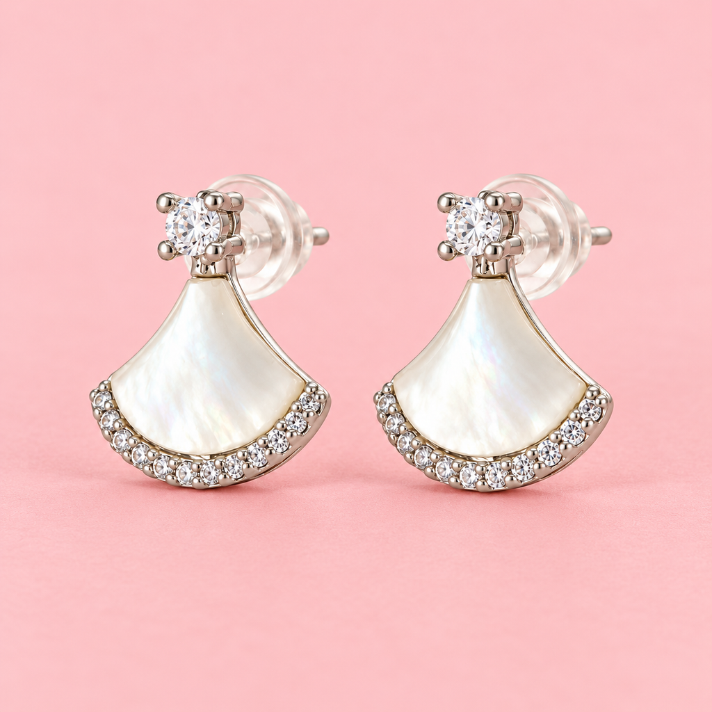 Silver-tone fan-shaped mother-of-pearl drop earrings with clear sparkling stone accents and round crystal studs displayed against a pink background.