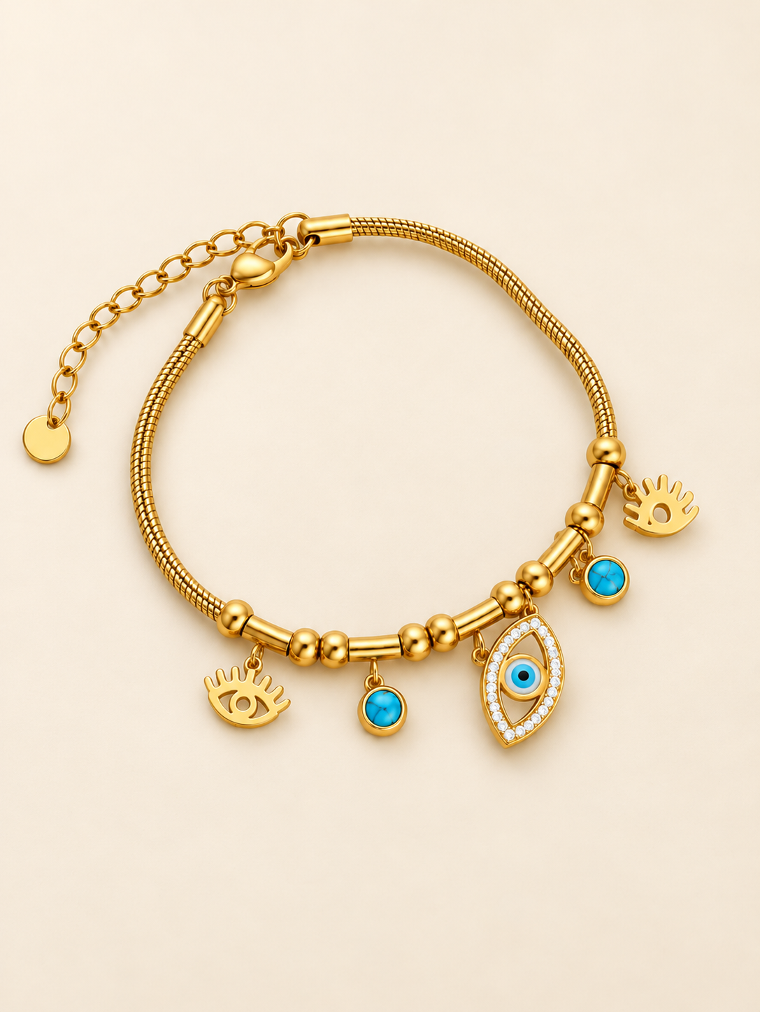 Gold-toned stainless steel charm bracelet featuring blue evil eye motifs, turquoise-coloured accents and an eye-shaped charm with sparkling white stones.
Decorative gold beads and a delicate chain with an adjustable extension, displayed on a clean pink background.