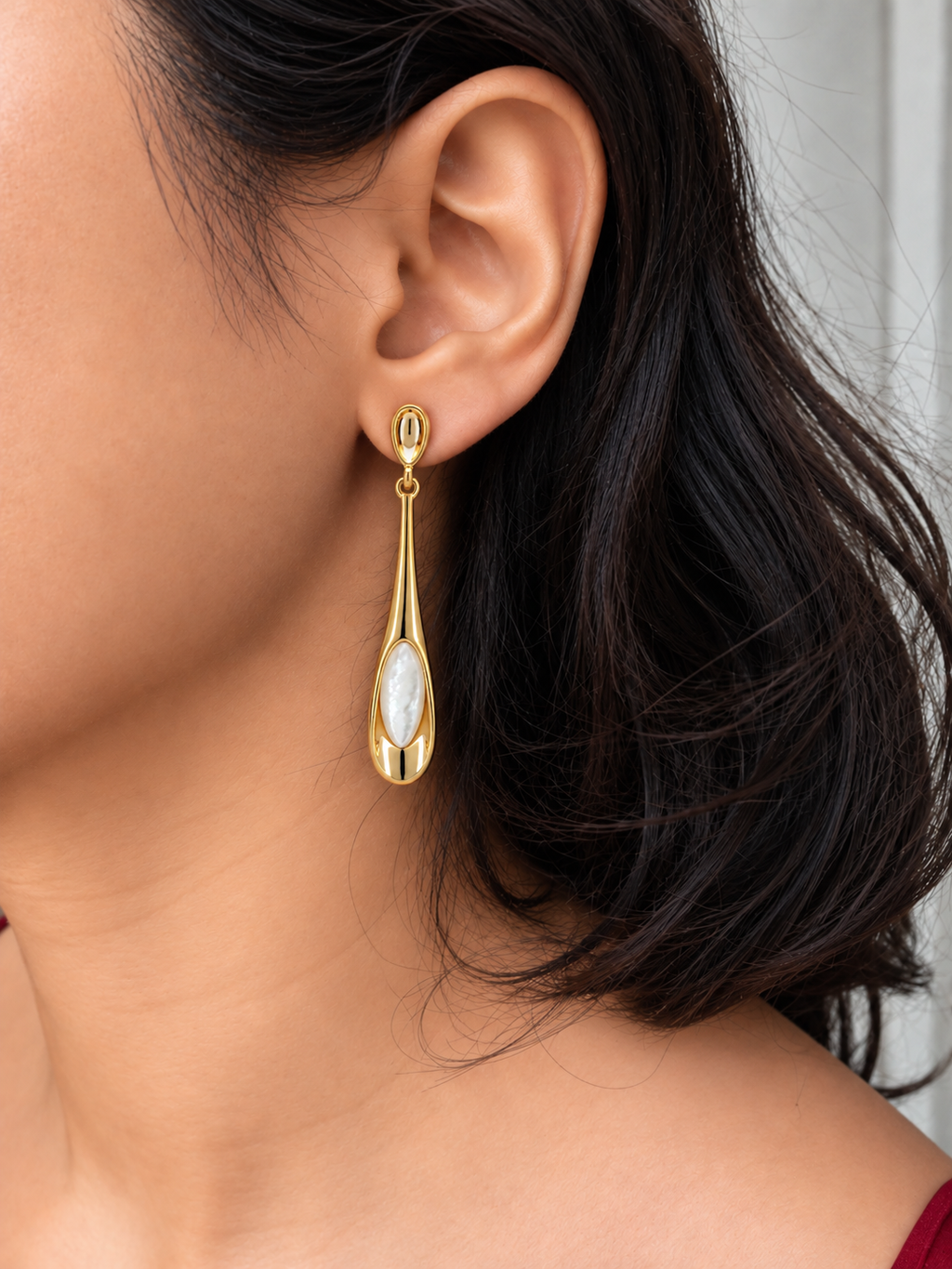 Gold-tone teardrop drop earrings with marquise-shaped white Mother of Pearl inlay and polished metal frame worn by a model.