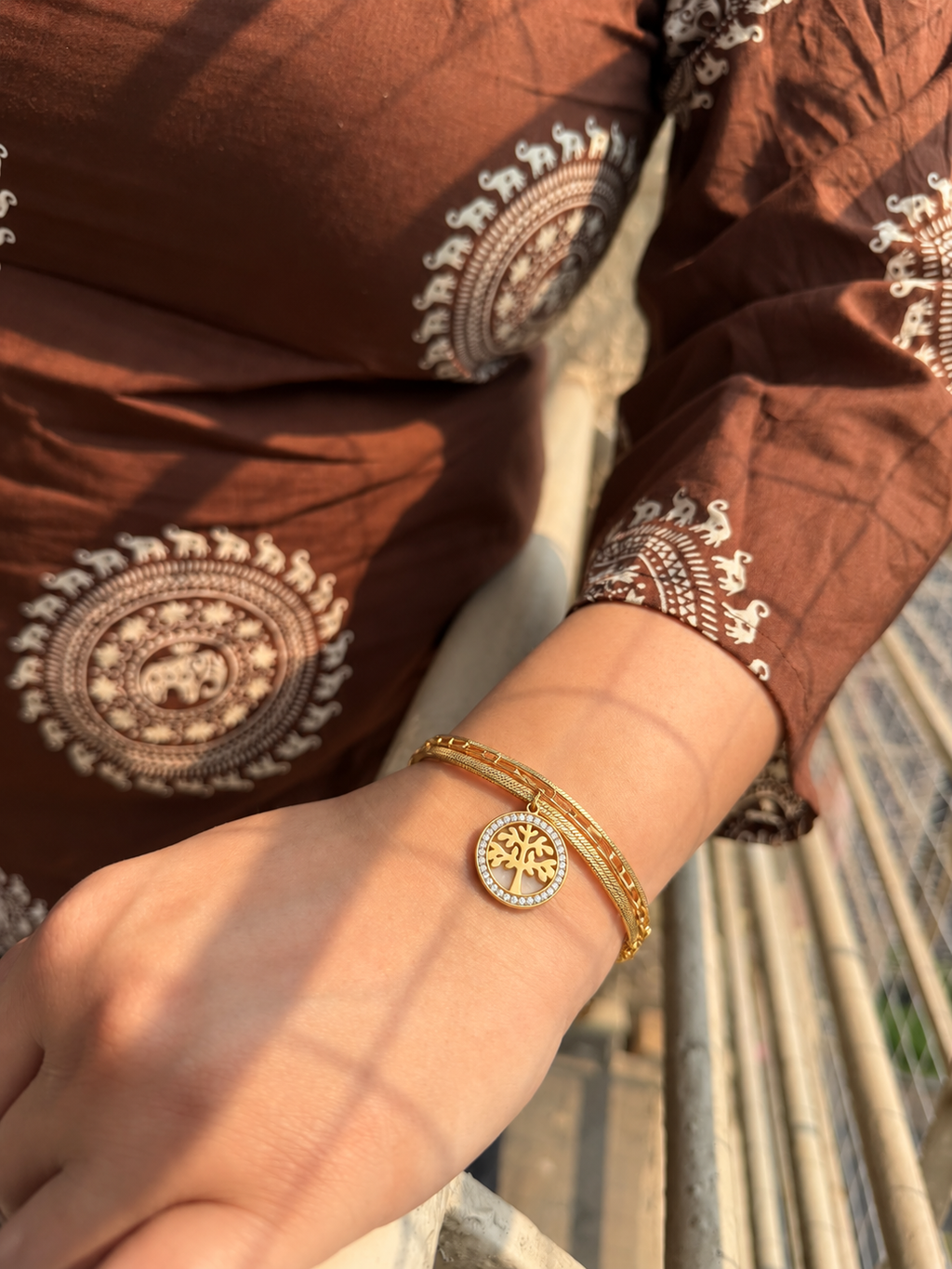 Gold-toned layered bracelet featuring a round Tree of Life charm with a border of clear sparkling stones.
Designed with a snake chain, rectangular-link chain and an adjustable extension clasp worn by a model.