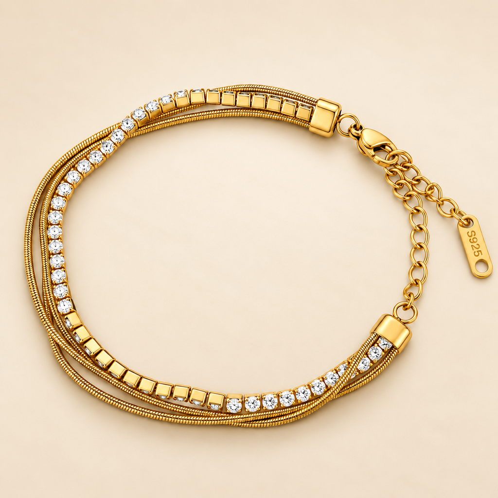 Gold-toned stainless steel multi-strand bracelet featuring clear sparkling stones and polished square accents.
Layered chain bracelet with an adjustable extension and lobster clasp, displayed on a clean pink background.