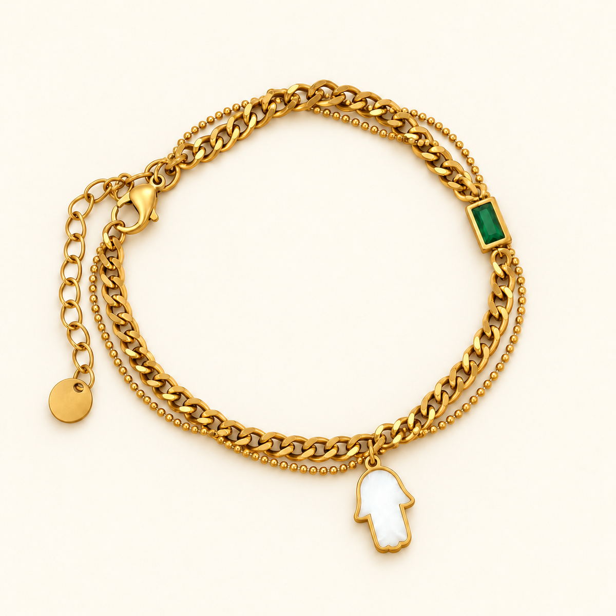 Gold-toned layered bracelet featuring a green rectangular accent and a white Hamsa hand charm.
Designed with chunky curb links, a delicate beaded chain and an adjustable extension clasp on a pink background.