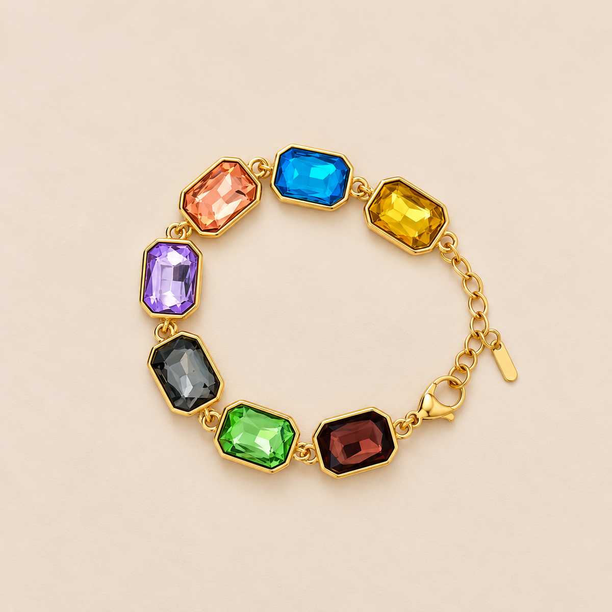 Gold-toned stainless steel bracelet featuring colourful rectangular faceted stones in blue, yellow, pink, purple, black, green and red.
Multicoloured gemstone-inspired bracelet with polished gold settings and an adjustable chain, displayed on pink background.