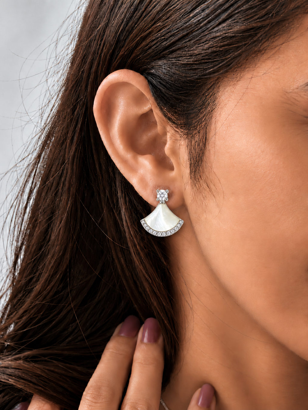 Silver-tone fan-shaped mother-of-pearl drop earrings with clear sparkling stone accents and round crystal studs worn by a model.