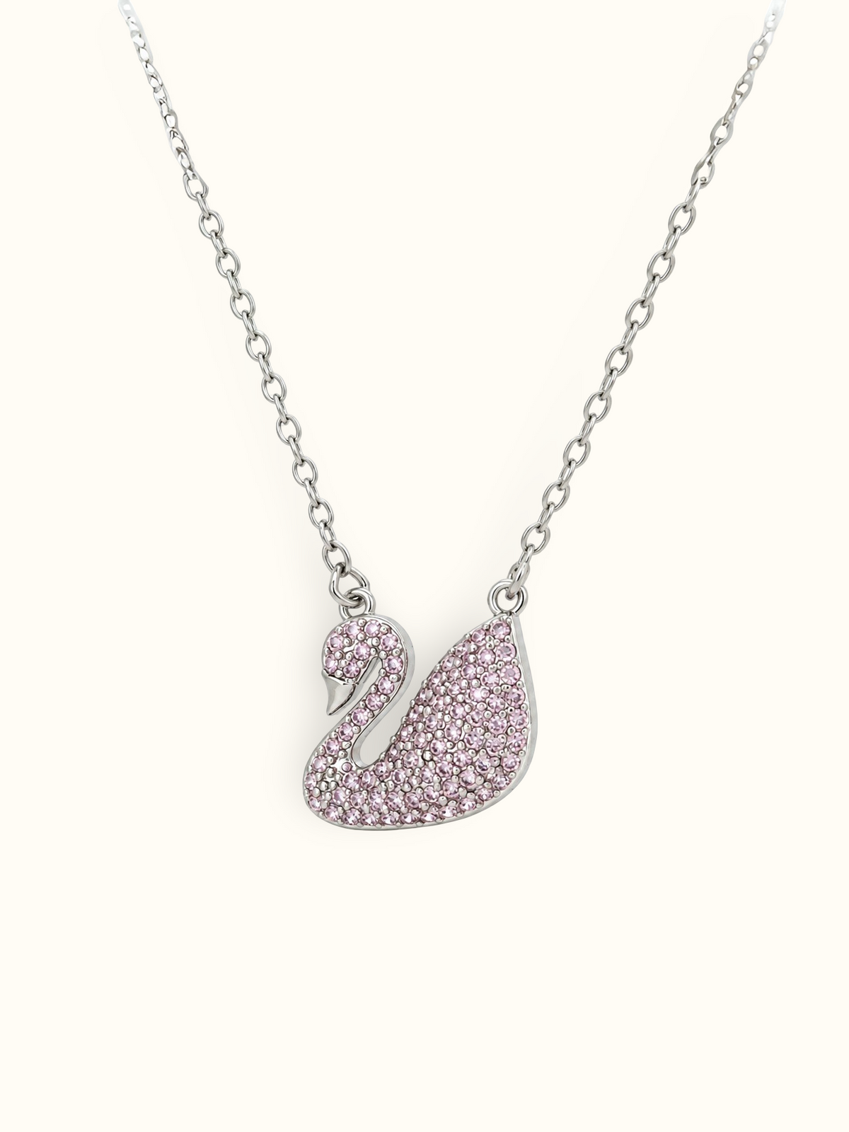 Silver-toned swan pendant necklace embellished with blush-pink sparkling stones and polished detailing.
Elegant pink swan charm suspended from a delicate silver-toned link chain against a white background.