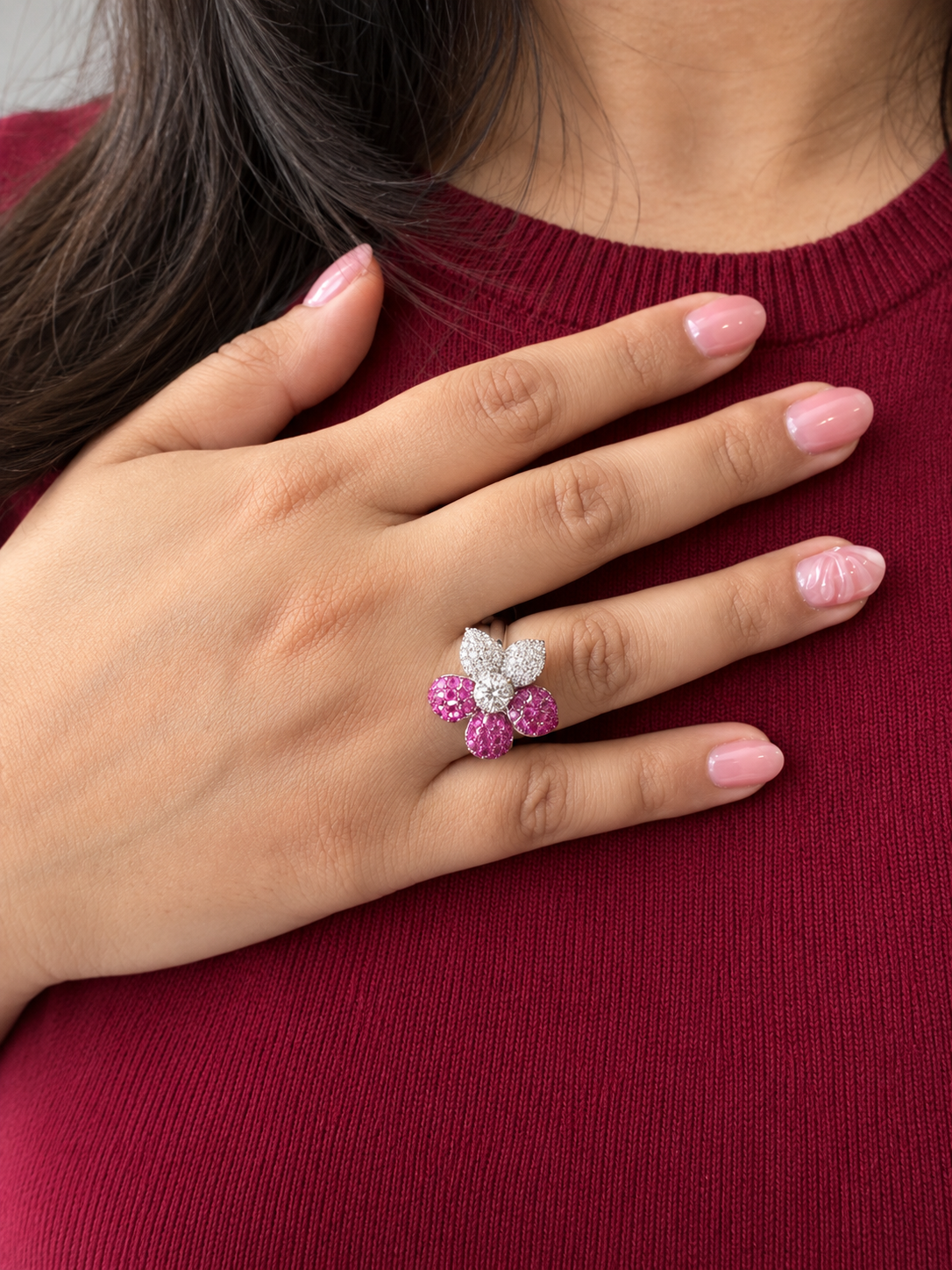 A model wearing the silver and pink petal flower ring on a red top