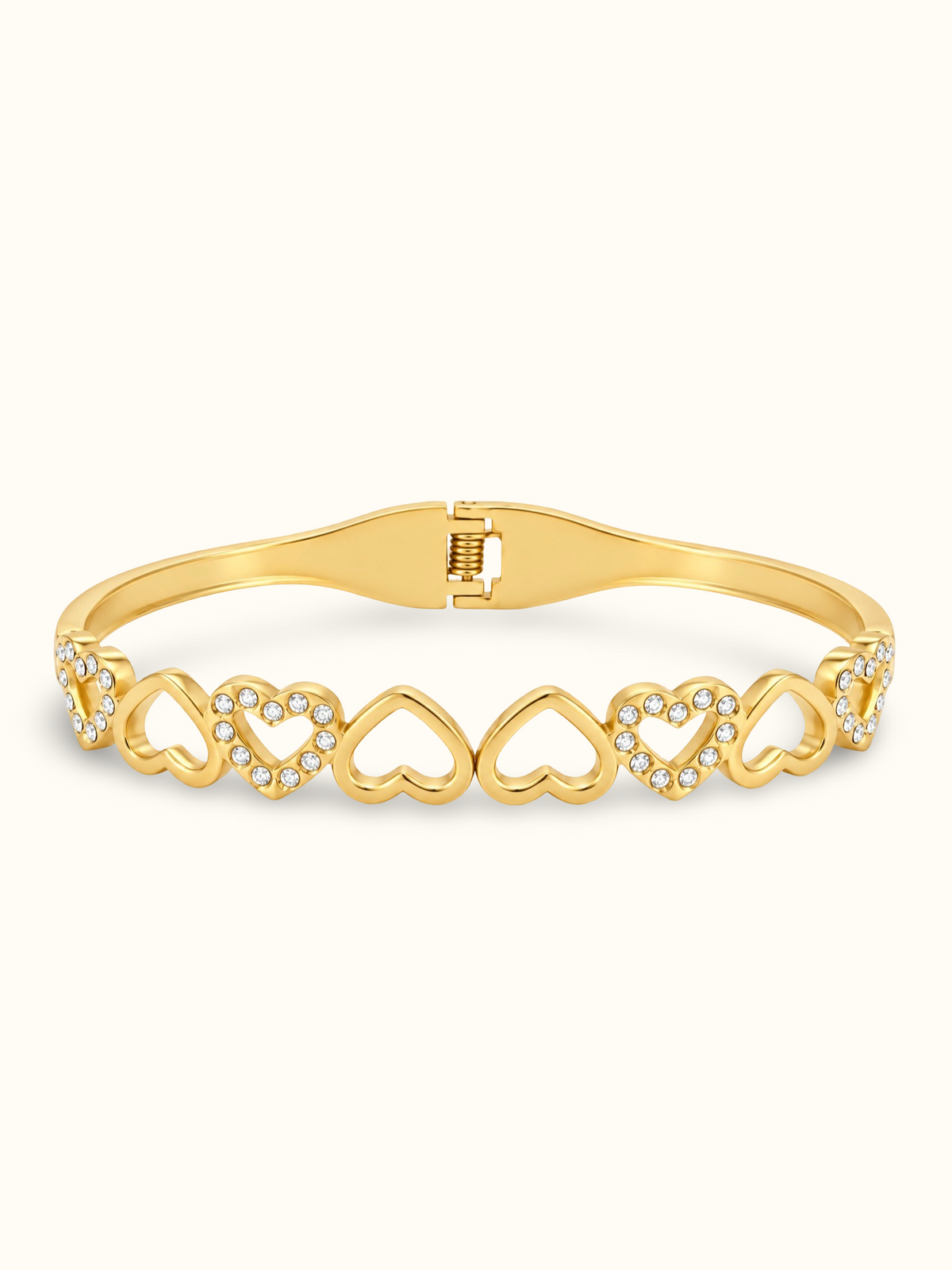 Gold-toned stainless steel bangle featuring alternating open-heart motifs with polished finishes and sparkling white stone accents with elegant hinged cuff design, displayed on a clean white background.
