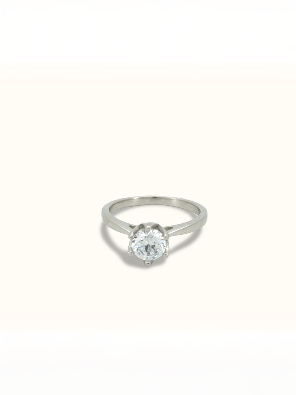 A classic solitaire engagement ring featuring a round brilliant-cut diamond set in a polished silver-colored band, centered against a clean, off-white background.