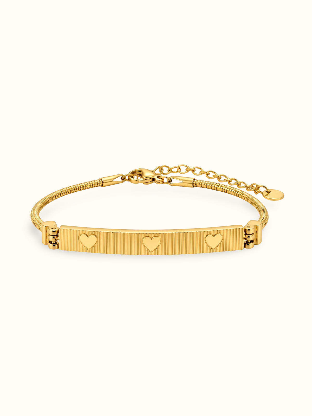 Gold-toned stainless steel bracelet featuring a textured rectangular bar with three engraved heart motifs.
Slim snake-chain bracelet with an adjustable extension, displayed on a clean white background.