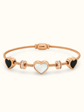Rose gold stainless steel bracelet featuring three heart charms with black and white inlays and sparkling stone accents on a flexible wire band against a white background. 