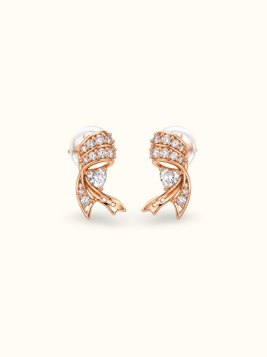 Rose gold-tone ribbon heart stud earrings featuring sparkling clear stones, heart-shaped crystal accents and intricate curved metal detailing displayed against a cream background.
