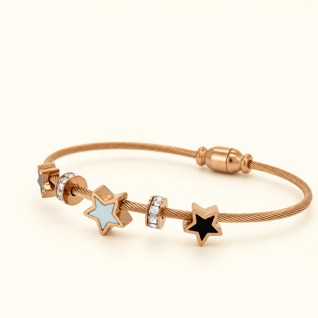 Rose gold-toned bracelet featuring three star charms with blue and black enamel details and sparkling crystal-accented spacers.
Celestial-inspired cable bracelet with a magnetic clasp, photographed against a clean, light pink background.