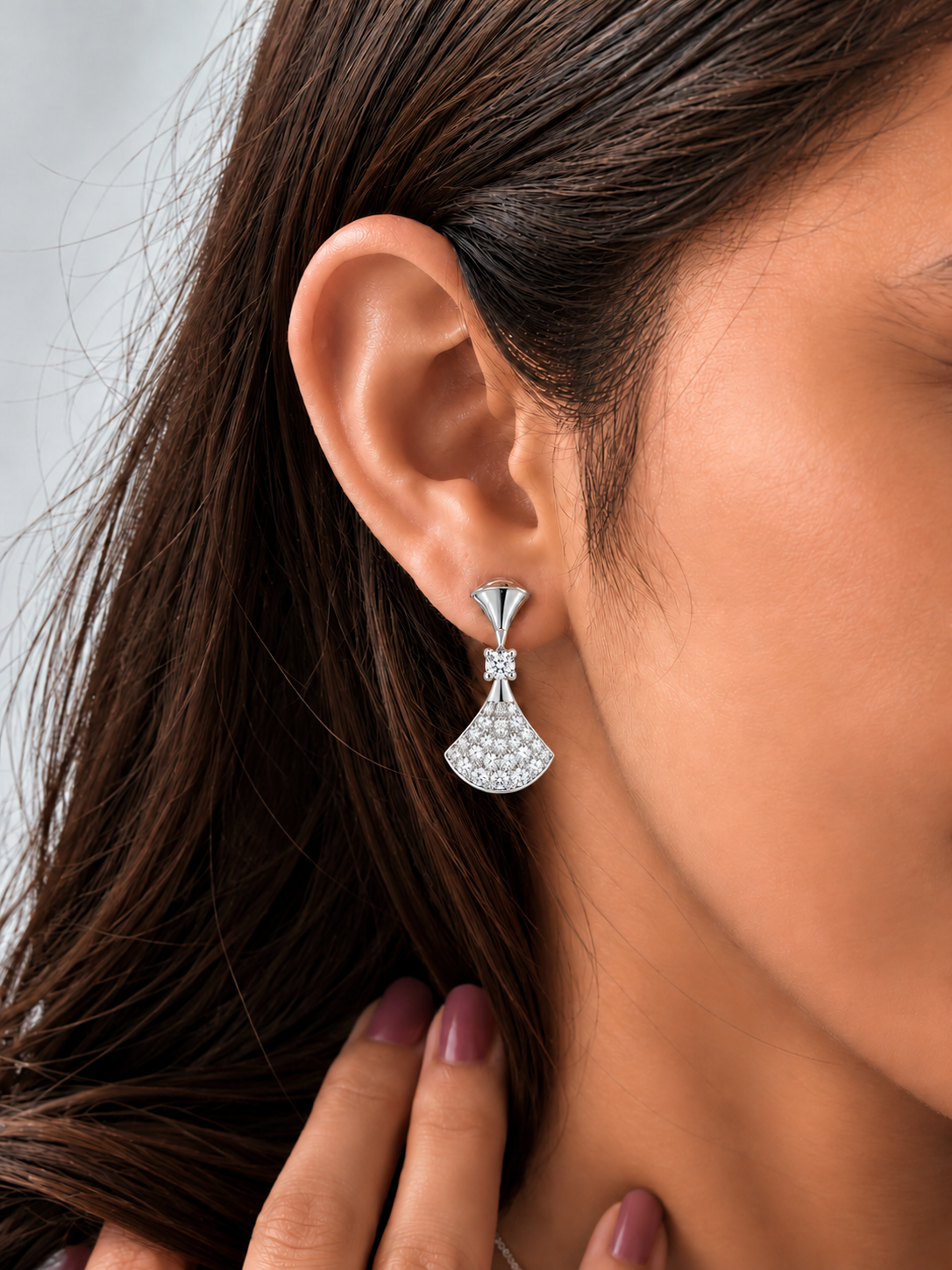 Model wearing silver-tone fan drop earrings embellished with clear sparkling stones.