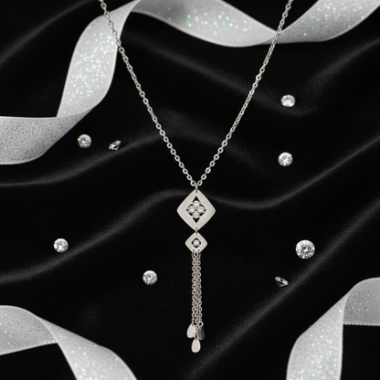 Silver necklace on a black fabric background with silver ribbons.