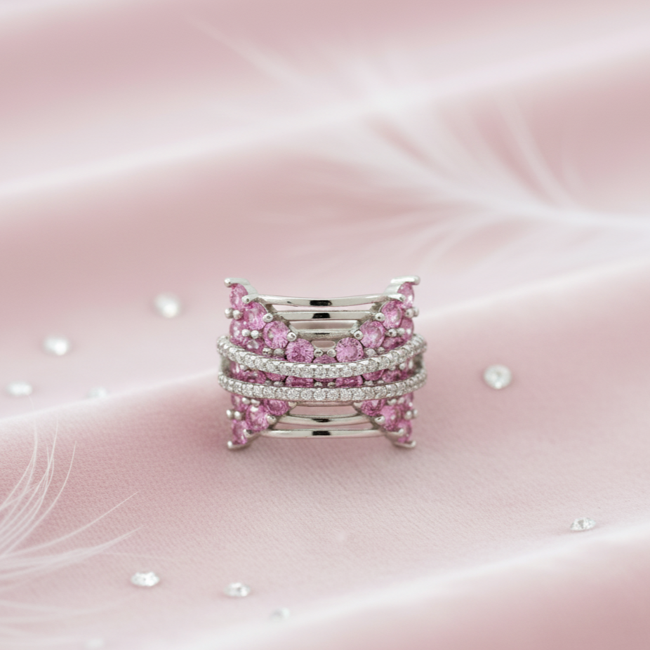 Stack of pink gemstone rings on a soft pink background. Alt: top view butterfly pink ring silver ring design with pave detailing