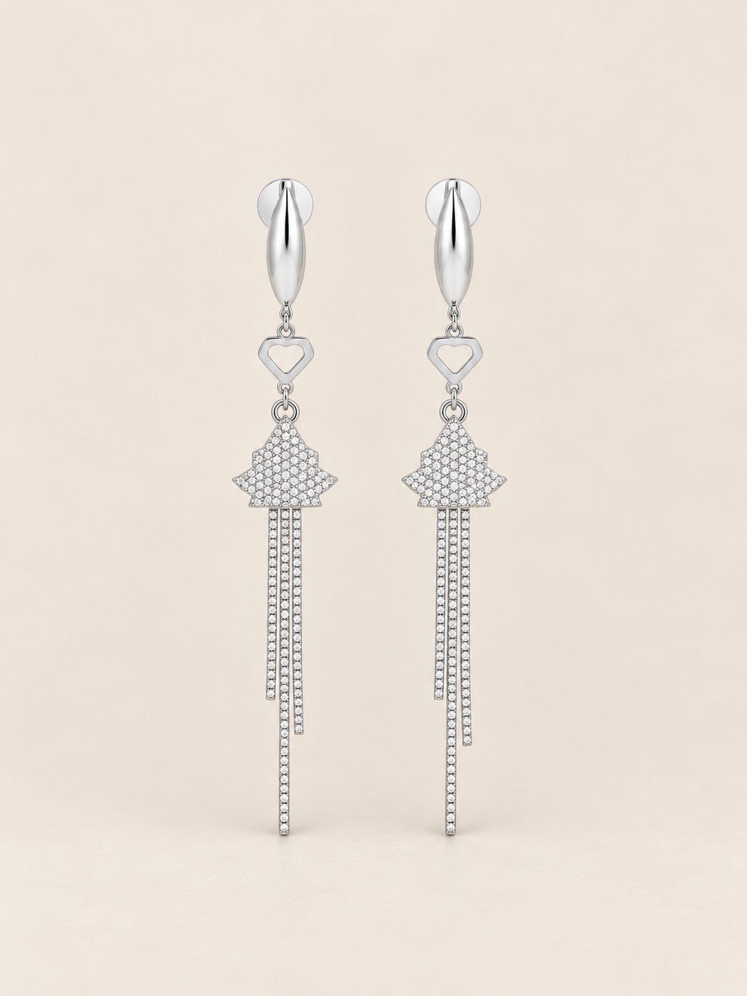 A pair of silver-toned dangle earrings with a textured geometric charm and cascading chain drops, shown against a solid light beige background.