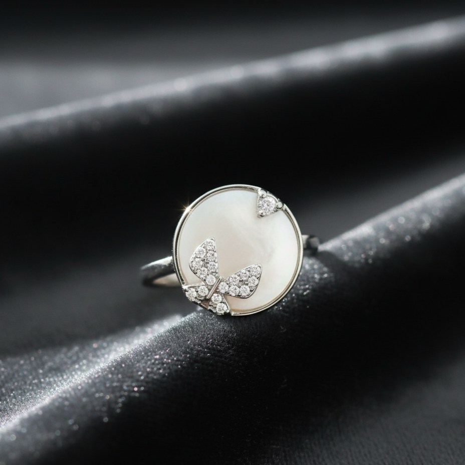 Silver ring with butterfly design on a dark surface