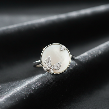 Silver ring with butterfly design on a dark surface