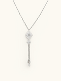A silver-toned dangle necklace featuring a diamond-shaped pendant set with clear stones, a smaller matching pendant, and two dangling chain drops with teardrop charms, shown on a plain off-white background.