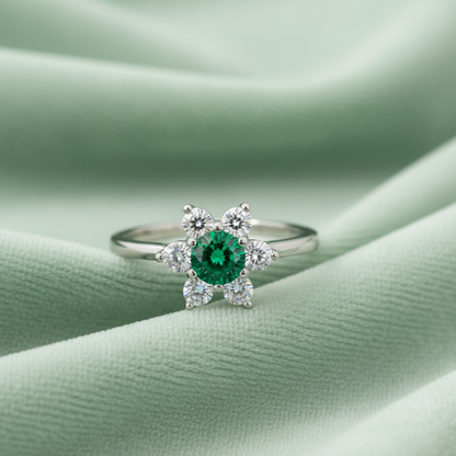 Silver ring with a green gemstone on a green fabric background