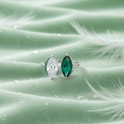 Emerald & Diamond Kiss Ring on a green fabric background