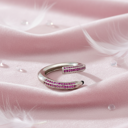 Silver ring with pink gemstones on a pink fabric background