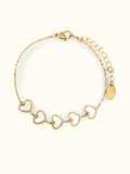 A gold chain bracelet featuring five interlocking hollow heart charms with white inlay, displayed on a clean off-white background.