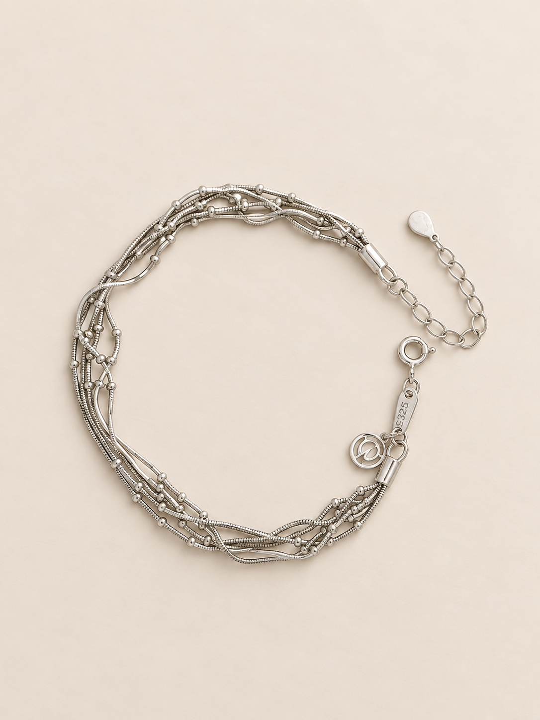 A multi-strand silver chain bracelet with a lobster clasp and extender chain, displayed on a light beige background.