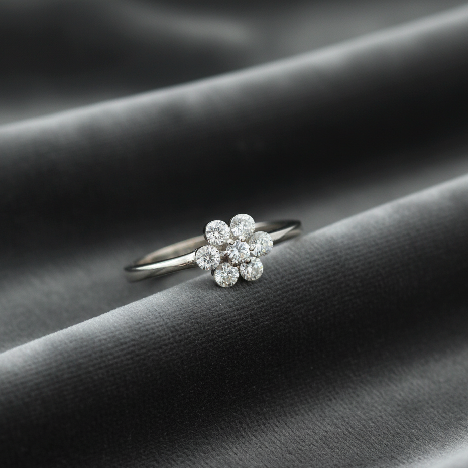 Silver ring with floral diamond design on a dark fabric background