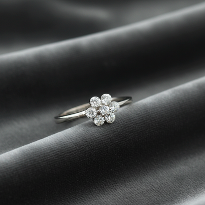 Silver ring with floral diamond design on a dark fabric background