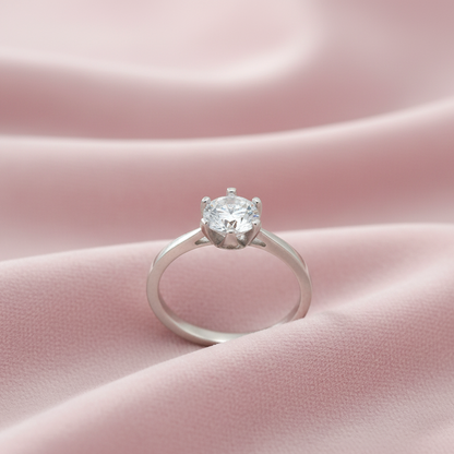 Silver ring with a diamond on a pink fabric background