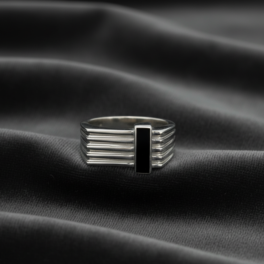 Silver ring with a black center on a black fabric background