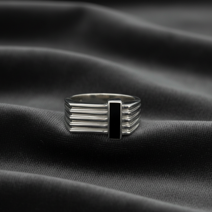 Silver ring with a black center on a black fabric background