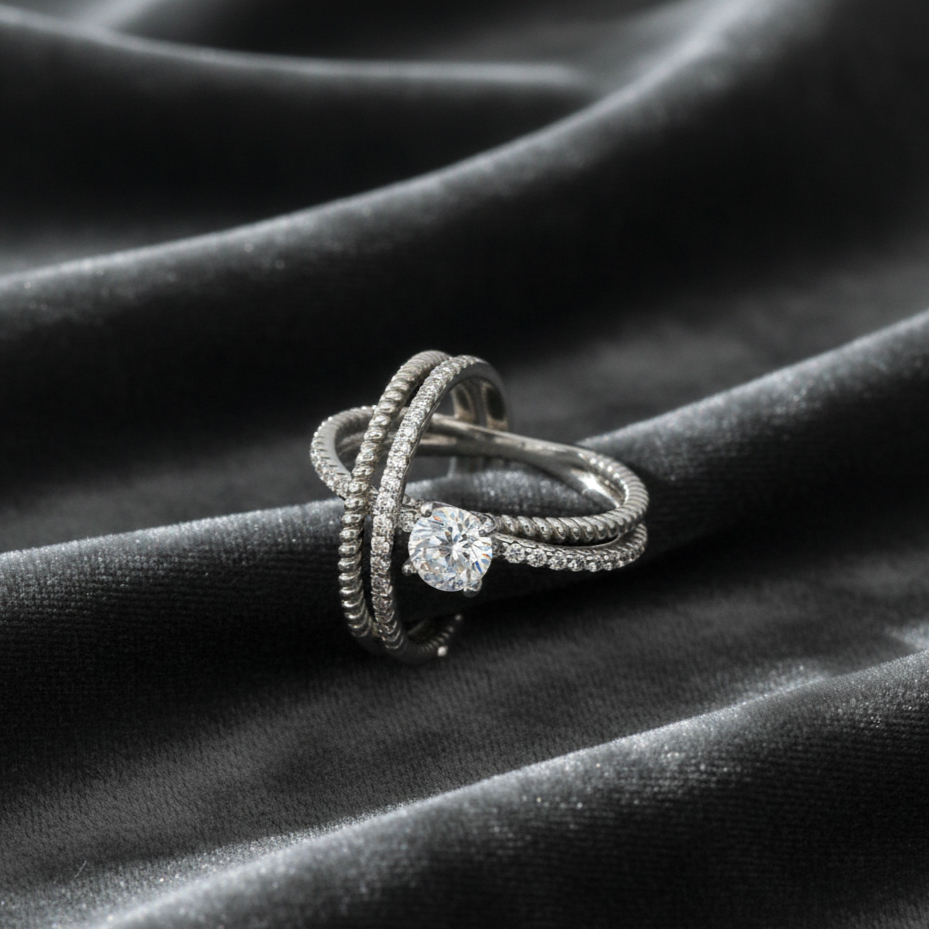 Silver ring with a diamond on a dark fabric background